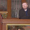 Ein Mann steht lächelnd vor einer Orgel